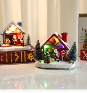 Detailed close-up of glowing resin Christmas house with festive snow and LED light effect