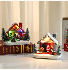 Close-up of lighted Christmas resin houses with Santa figures and snowy bases on a book