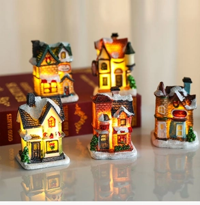 Macro view of glowing miniature Christmas resin houses with snowy texture and warm LED lights