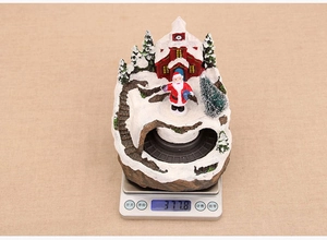 Detailed view of musical rotating Christmas resin ornament on scale weighing 377.8g