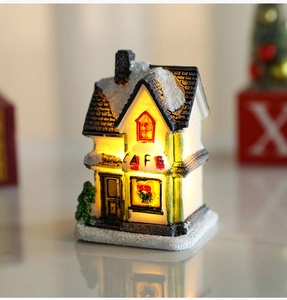 Close-up of lighted resin Christmas cafe cottage with warm LED glow and snow effect