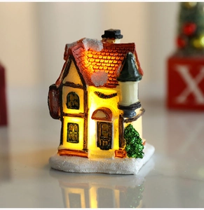 Detailed close-up of a glowing Christmas resin house with snow effects and warm LED lights
