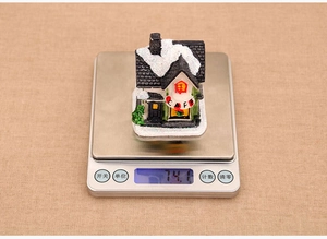 Miniature snowy cafe house resin decoration weighing 74.1 grams on a digital scale