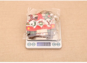 Three Christmas gnomes on a wooden red truck ornament weighing 33.7 grams on a digital scale