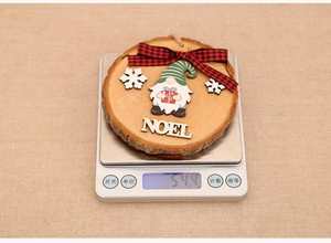 Dettaglio decorazione natalizia in legno con gnomo e scritta Noel su una bilancia