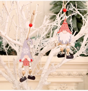 Detail of wooden Christmas gnome ornaments with beaded legs hanging on white tree branches