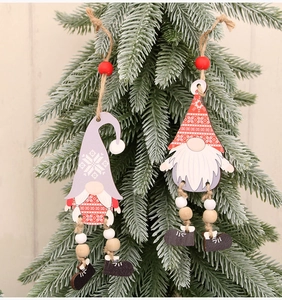 Detail of wooden gnome ornaments with beaded legs hanging on green pine tree branches