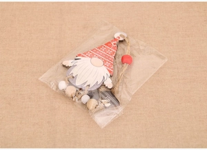 Close-up of wooden Christmas gnome ornament with red snowflake hat and twine bead string