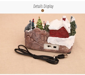Detail display of Christmas resin house ornament showing USB power port and cable