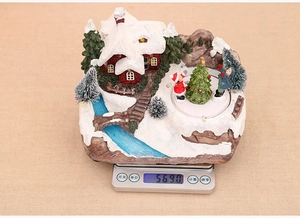 Detailed view of musical Christmas snow house ornament on scale weighing 569.0g