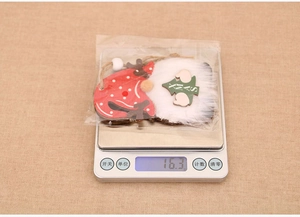 Detail view of a wooden Christmas gnome ornament on a digital scale weighing 16.3 grams
