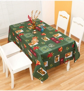 Close-up of dark green Christmas tablecloth with Santa, gold bells and wavy edge