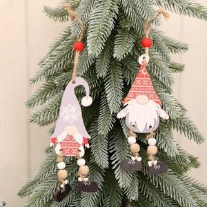 Wooden Christmas gnome ornaments with dangling legs hanging on a festive green pine tree