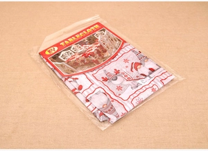 Folded Christmas tablecloth in packaging featuring gnome, reindeer, and snowflake motifs