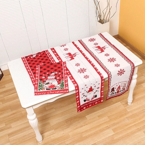Set di tre runner natalizi con motivi di gnomi e renne su tavolo in legno bianco