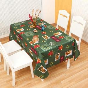 Christmas tablecloth with green festive patterns and scalloped edges on dining table