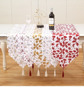 Detailed close-up of festive Christmas table runners with gold foil patterns and tassel fringe