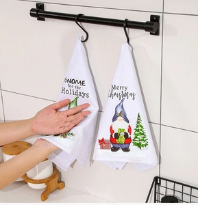Weihnachtliche Handtücher mit Wichtel-Motiv und Metallhaken an einer weißen Fliesenwand