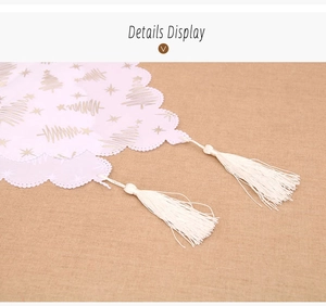 Detail of Christmas table runner with golden trees, wavy edges and white tassels