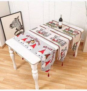 Detail of Christmas knitted table runner featuring festive gnomes and red tassel edges