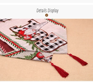 Detail of Christmas table runner with gnome embroidery, JOY lettering, and red tassels