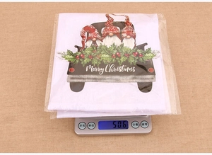 Christmas hand towel featuring cute gnomes on a truck, weight shown on a scale