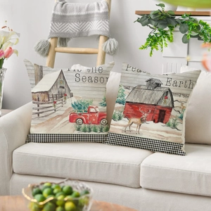 Detail of Christmas pillow covers with rustic barn and truck illustrations on sofa