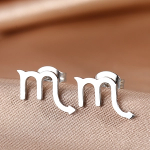Macro view of Scorpio zodiac symbol stud earrings in silver stainless steel on silk
