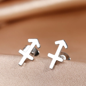 Macro view of Sagittarius zodiac stud earrings on champagne silk background