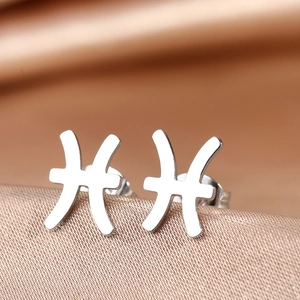 Detailed view of silver Pisces zodiac stud earrings on champagne silk background