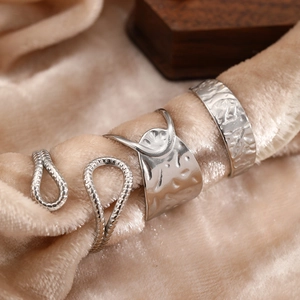 Macro detail of silver geometric rings set on beige velvet fabric for a modern minimal look