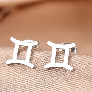 Polished silver stainless steel Gemini zodiac sign stud earrings on silk background