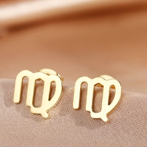 Macro shot of gold polished Virgo constellation stud earrings on silk fabric