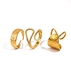 Three-piece gold geometric ring set with hammered textures and twisted crossover designs