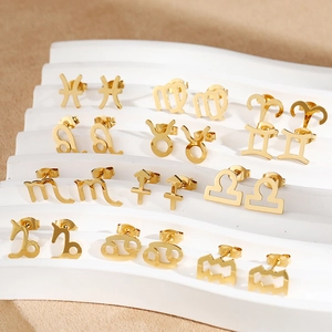 Golden 12 zodiac constellation stud earrings set displayed on a white textured stand