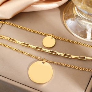 Detailed view of triple-layered gold stainless steel necklaces with round coin pendants