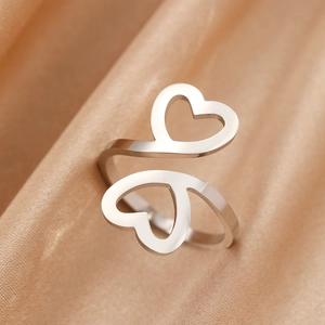 Bague ouverte double cœur en acier poli sur fond de satin de soie champagne