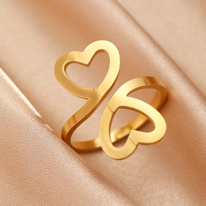 Vue macro d'une bague dorée à double cœur évidé sur fond élégant en satin champagne