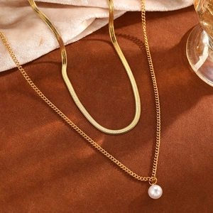 Détail d'un collier double rang en or avec pendentif perle blanche sur fond en velours