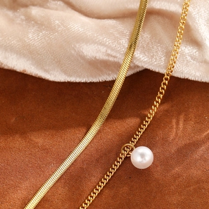 Détail du collier double couche plaqué or 18K avec chaîne serpent et perle blanche