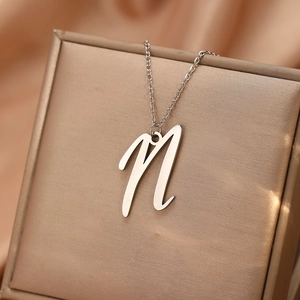 Gros plan du collier avec pendentif lettre M en acier argenté sur un écrin à bijoux