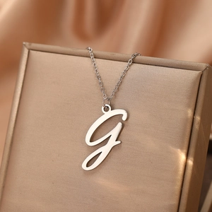 Vue macro du pendentif lettre G argentée sur une fine chaîne avec un fond en satin