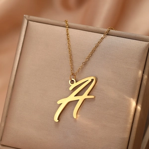 Détail macro du pendentif lettre A cursive sur fine chaîne dorée et boîte à bijoux