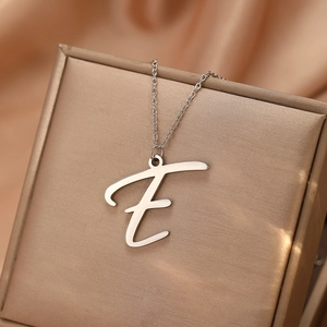Gros plan du pendentif lettre E argenté sur une fine chaîne sur une boîte à bijoux