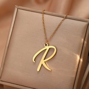Vue macro d'un collier avec pendentif lettre R dorée sur un coffret cadeau de luxe