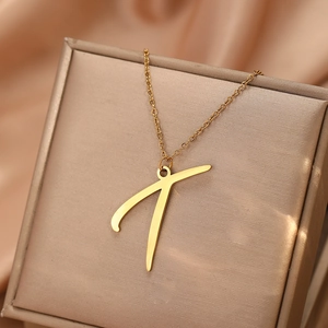 Détail d'un collier avec pendentif initiale dorée sur un écrin de bijoux en soie