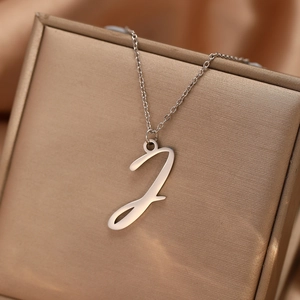 Vue macro du collier avec pendentif lettre J argentée sur détail de satin de luxe