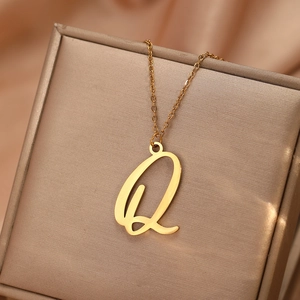 Gros plan d'un pendentif lettre Q dorée polie sur une chaîne fine et soie douce