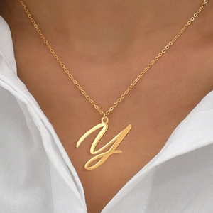 Détail d'un collier doré avec pendentif initiale Y poli porté par un mannequin