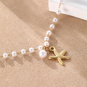 Collier de perles blanches pour femme avec pendentif étoile de mer dorée sur fond de sable